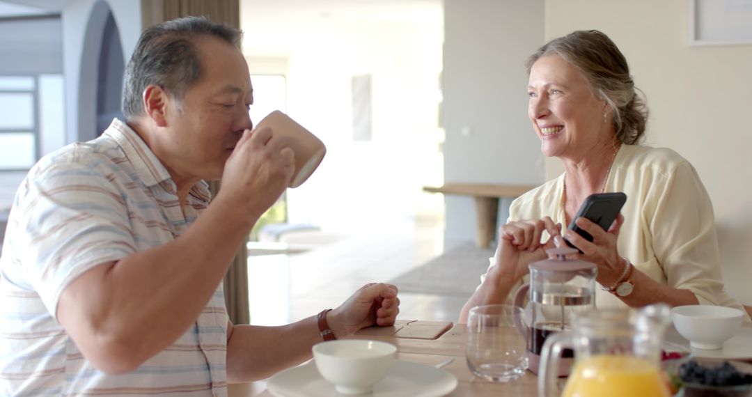 Senior Couple Enjoys Relaxing Breakfast with Smartphone Technology