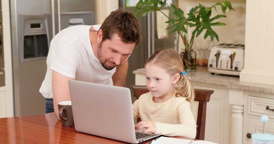 Father helping young daughter with online learning using laptop in kitchen - Free Images, Stock Photos and Pictures on Pikwizard.com