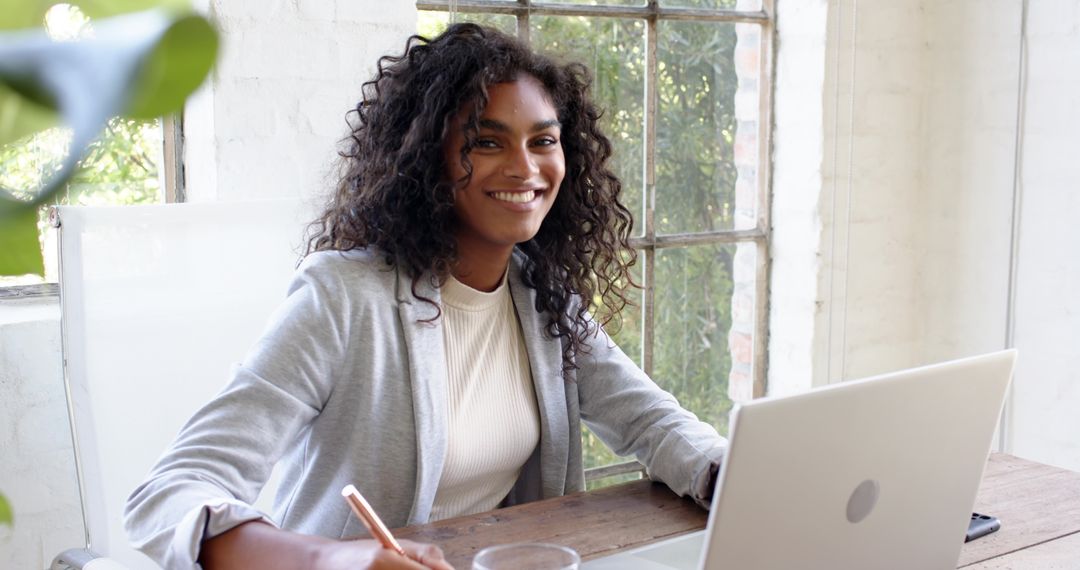 Smiling Woman Working at Home Office Desk with Laptop and Notebook
