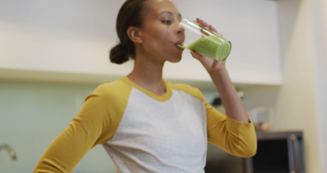 Biracial woman drinking healthy drink in kitchen - Free Images, Stock Photos and Pictures on Pikwizard.com