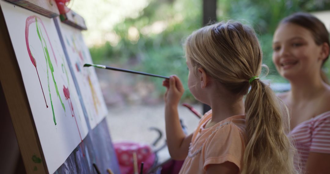 Young Girl Painting on Canvas with Her Friend Watching - Free Images, Stock Photos and Pictures on Pikwizard.com