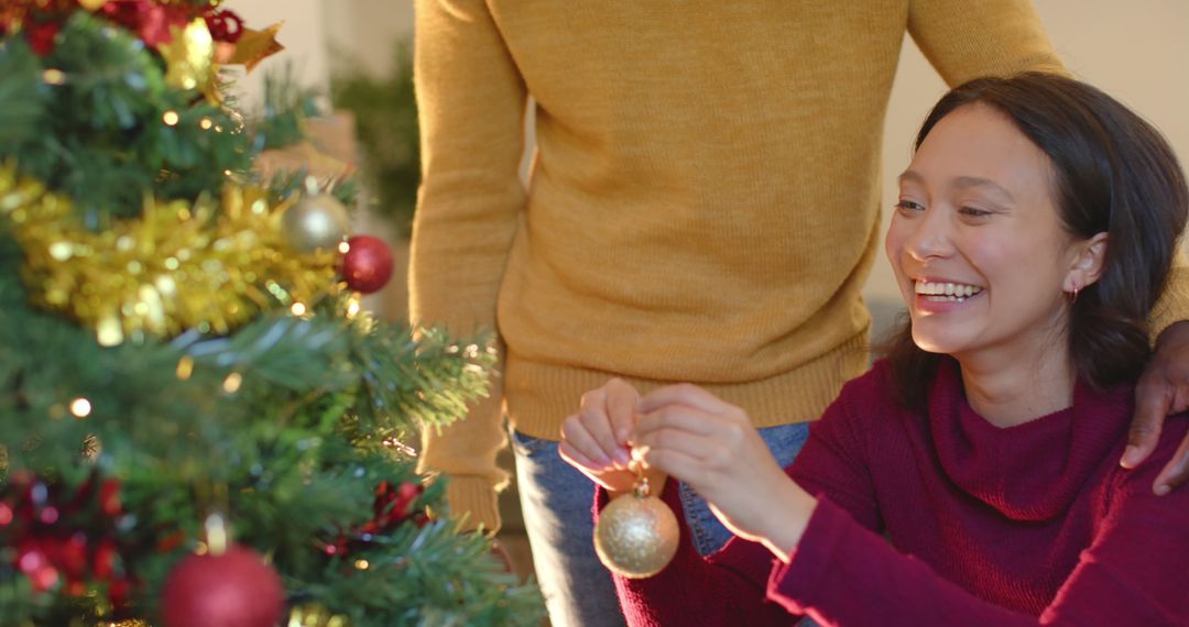 Interracial Couple Decorating Christmas Tree Together Inside Cozy Home - Free Images, Stock Photos and Pictures on Pikwizard.com