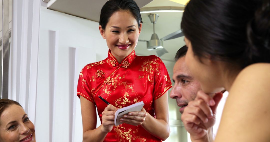 Diverse Group Ordering Food from Smiling Chinese Waitress in Traditional Dress