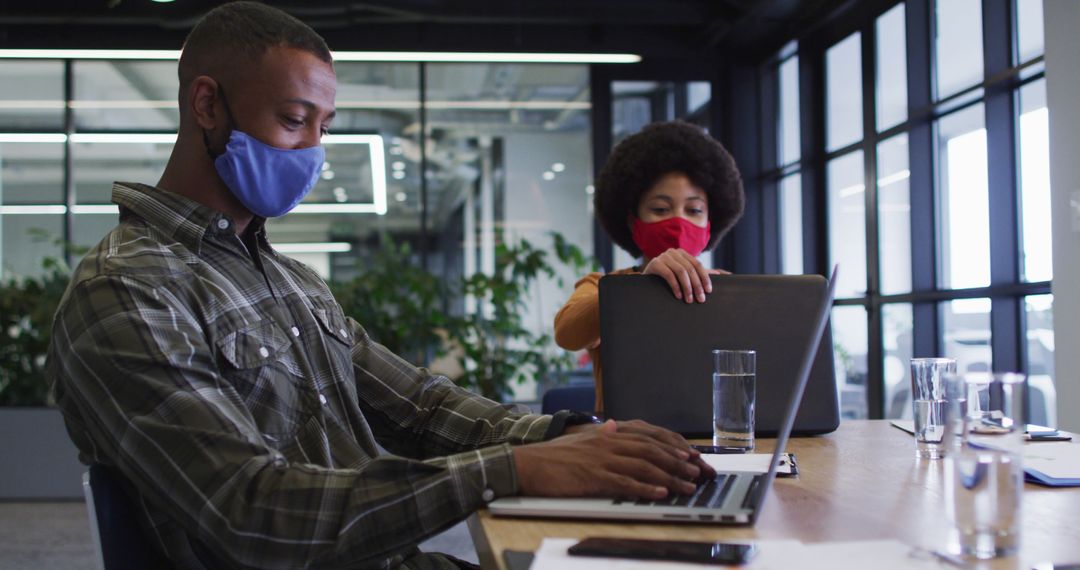 Diverse Colleagues Working with Laptops and Masks in Modern Office