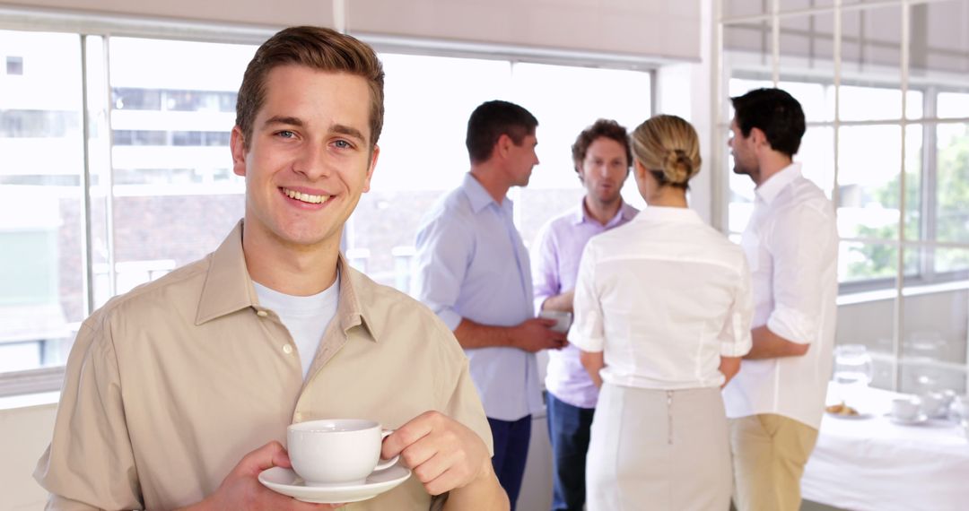 Smiling businessman holding coffee at office social event - Free Images, Stock Photos and Pictures on Pikwizard.com