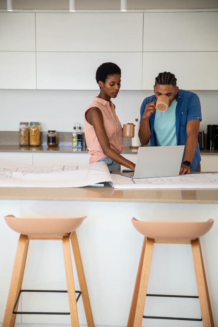 Couple Collaborating on Blueprints in Modern Kitchen Interior