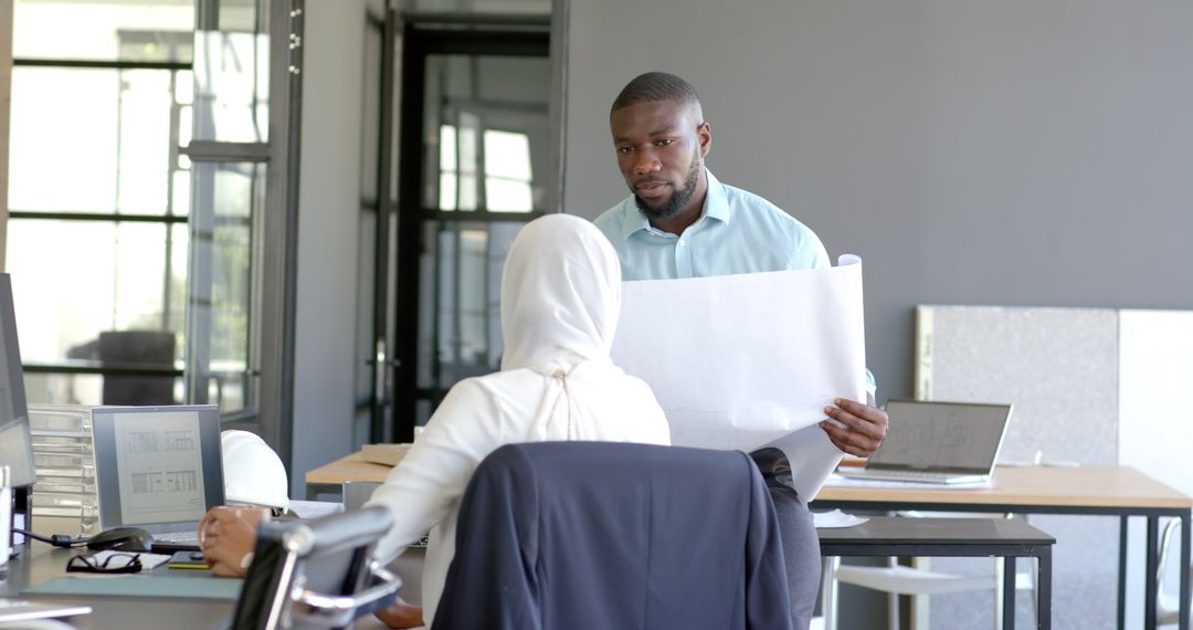 Diverse Professionals Reviewing Blueprints in Modern Workspace