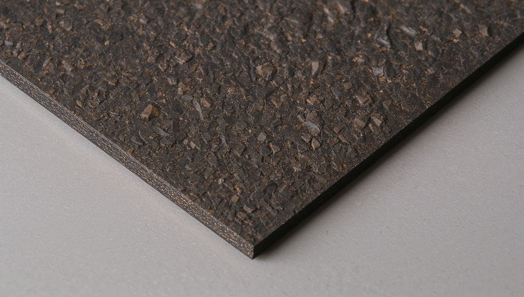 Dark Granular Panel Close-up Showing Layered Edge and Textured Speckled Surface Material