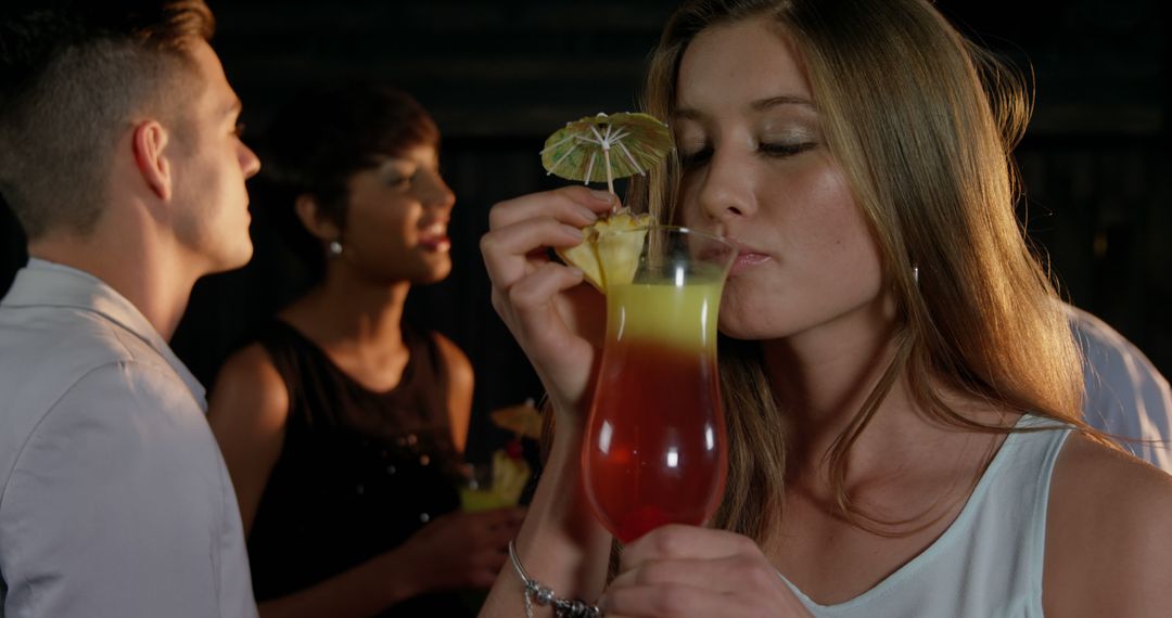 Young Woman Drinking Tropical Cocktail at Evening Party - Free Images, Stock Photos and Pictures on Pikwizard.com