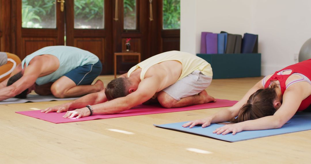 Diverse Group Practicing Yoga Poses in Health Studio