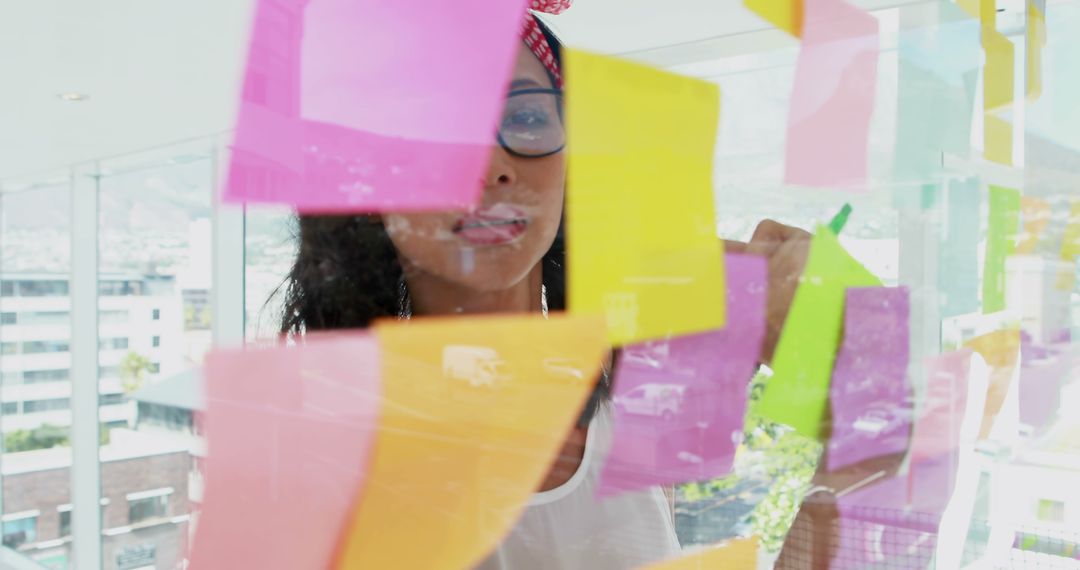 Female Professional Brainstorming with Colorful Sticky Notes on Glass Wall - Free Images, Stock Photos and Pictures on Pikwizard.com