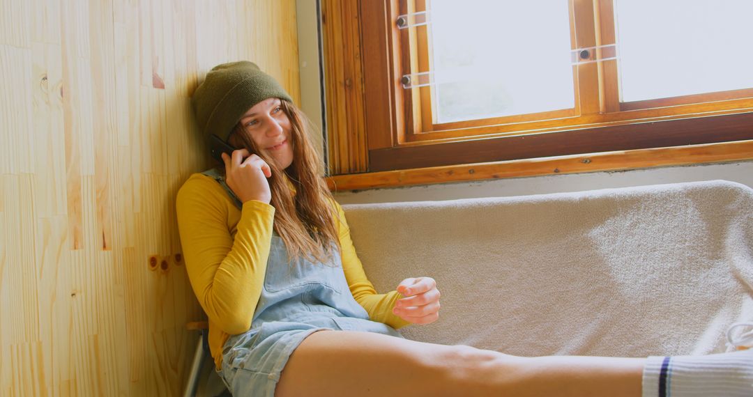 Young Woman Relaxing And Chatting On Phone By Window At Home - Free Images, Stock Photos and Pictures on Pikwizard.com