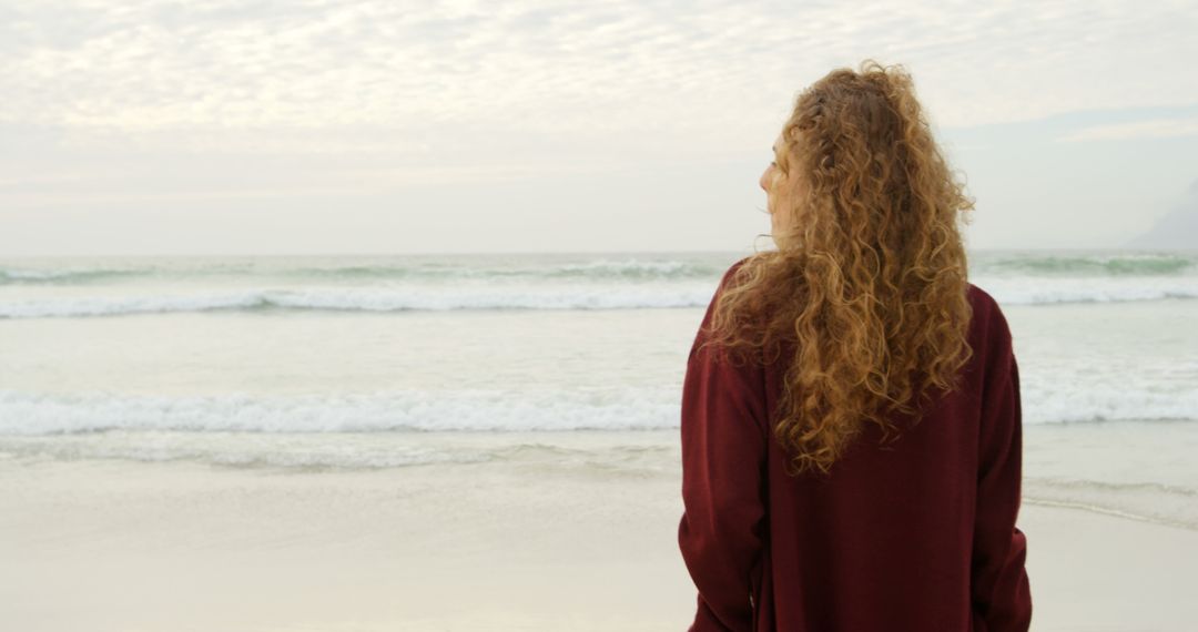 Woman with Curly Hair Looking at Sea during Cloudy Day - Free Images, Stock Photos and Pictures on Pikwizard.com