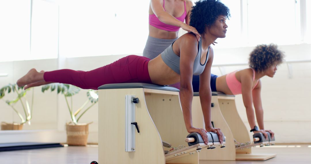 Women Practicing Pilates in Modern Fitness Studio with Instructor