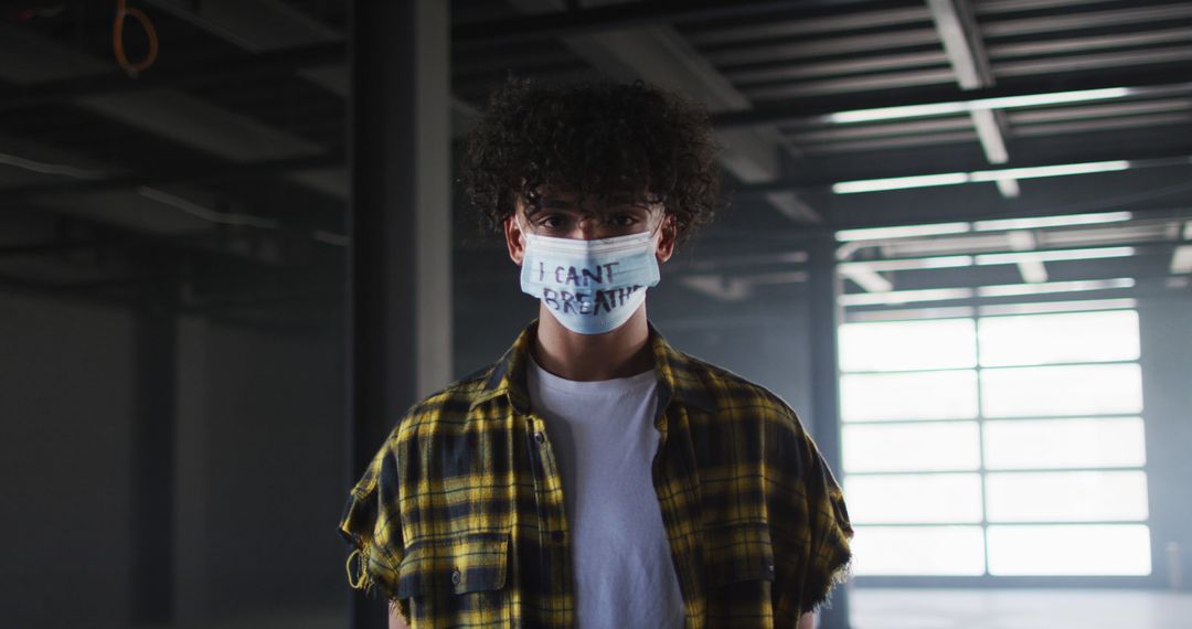 Young Man Wearing Protest Mask with 'I Can't Breathe' Text in Warehouse - Free Images, Stock Photos and Pictures on Pikwizard.com