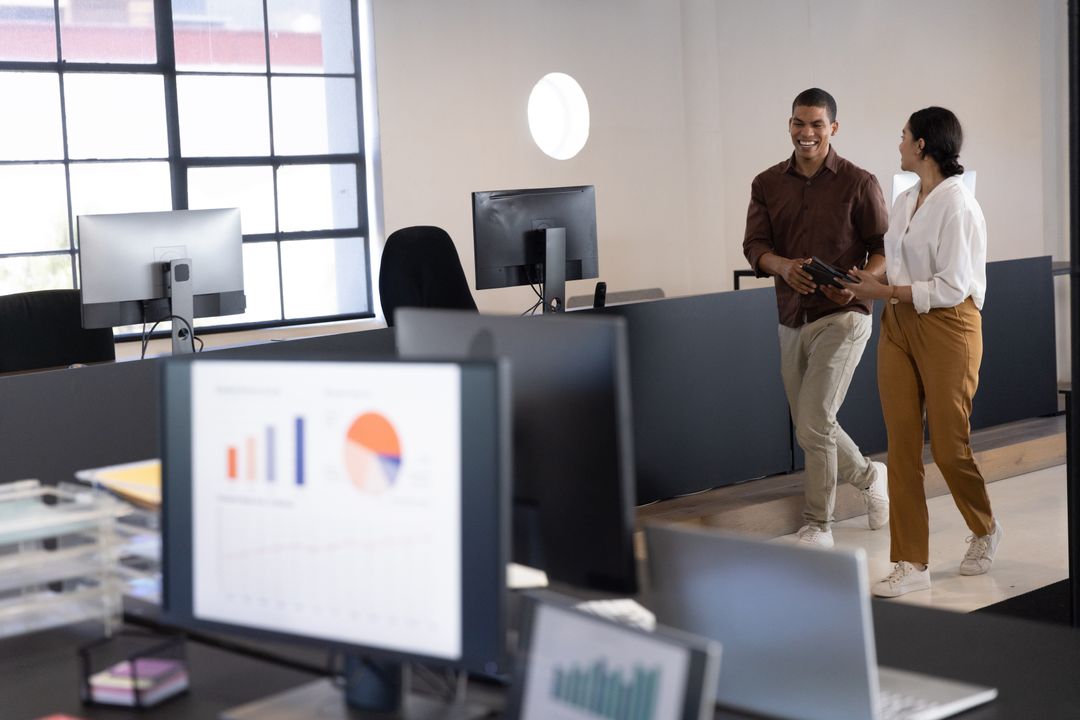 Diverse Colleagues Discussing Tech in Open Workspace