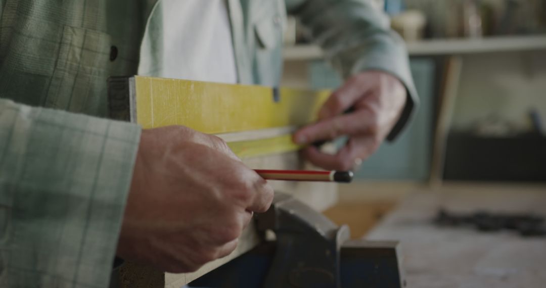 Focused Carpenter Marking Wood in Workshop