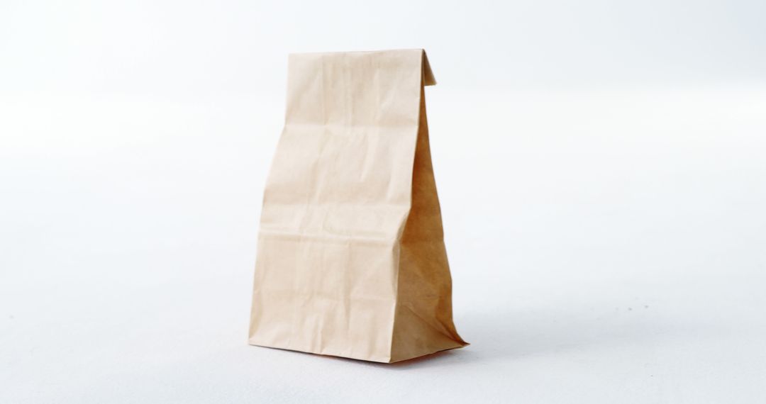 A plain brown paper bag stands upright against a white background, with copy space - Free Images, Stock Photos and Pictures on Pikwizard.com