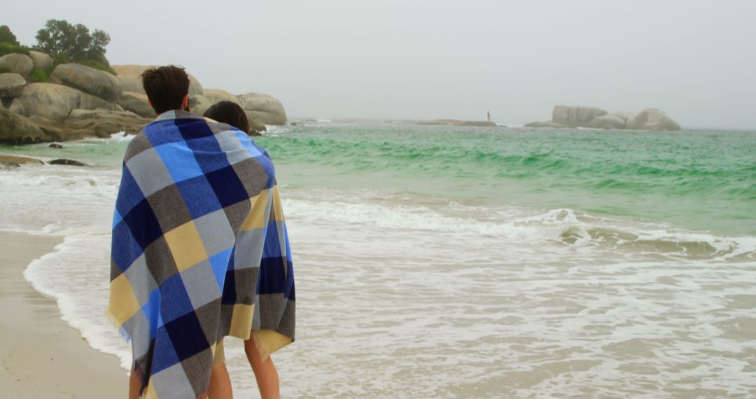 Couple Wrapped in Blanket Strolling on Misty Beach