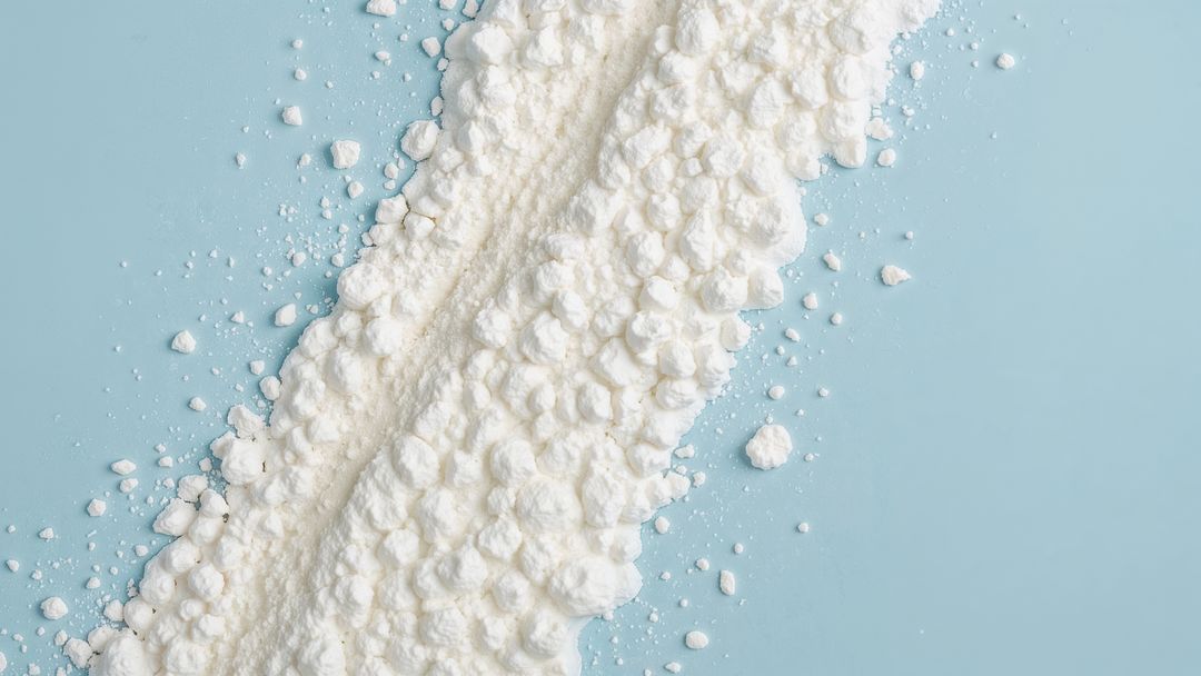 White milk powder texture on pastel surface creating abstract pattern