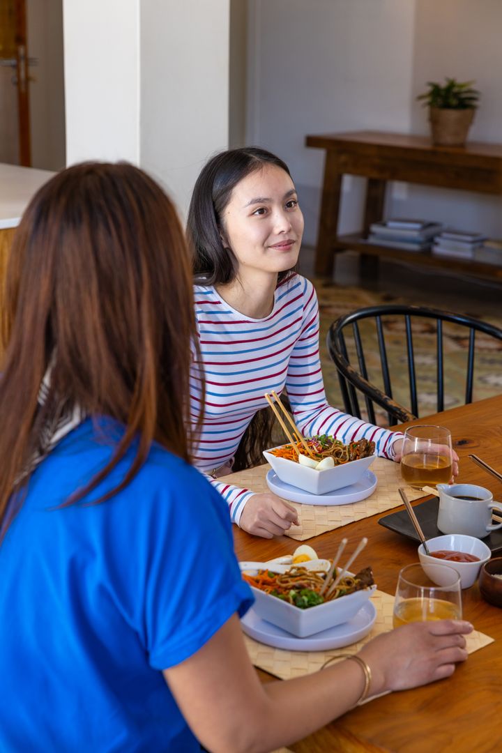 Mother and Daughter Enjoying Meal and Conversation at Home Dining Table