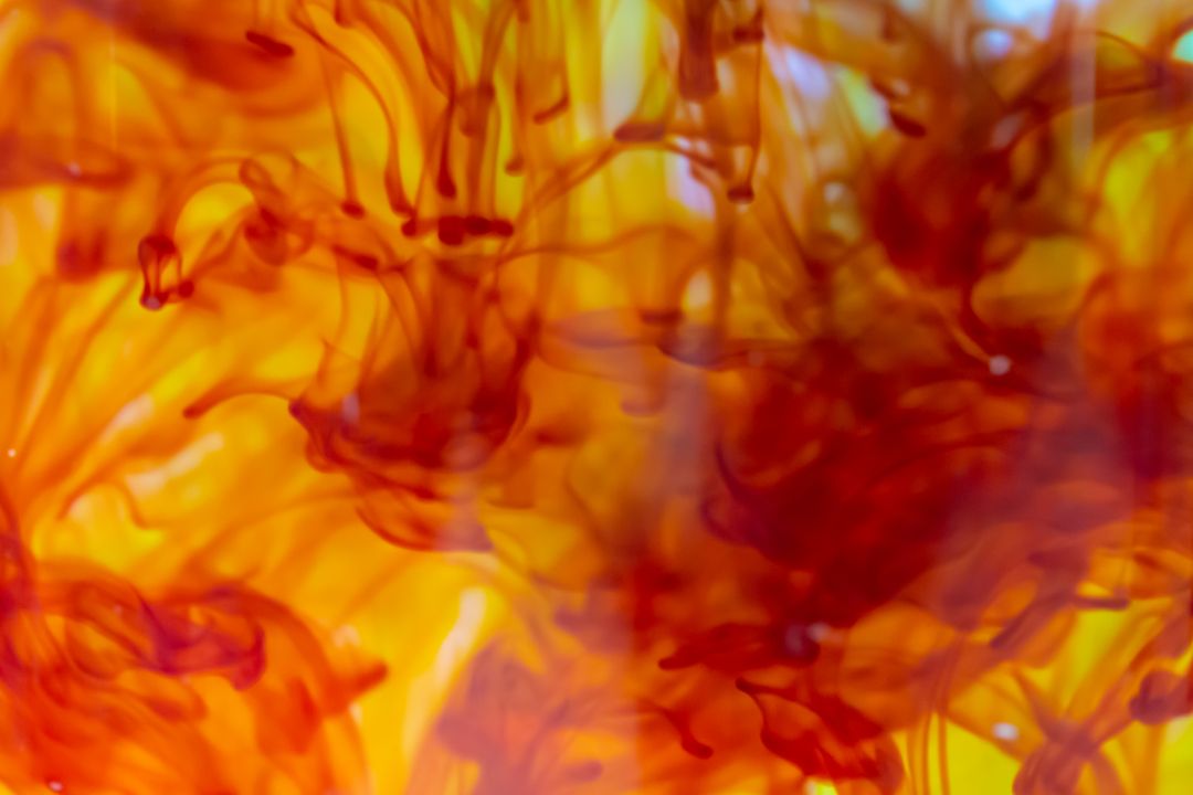 Fiery ink flowing in liquid with vibrant red and yellow swirls for abstract background