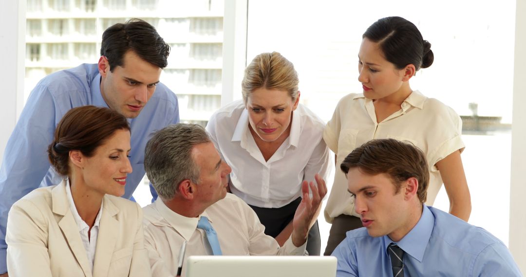 Diverse Business Team Collaborating Over Laptop at Office