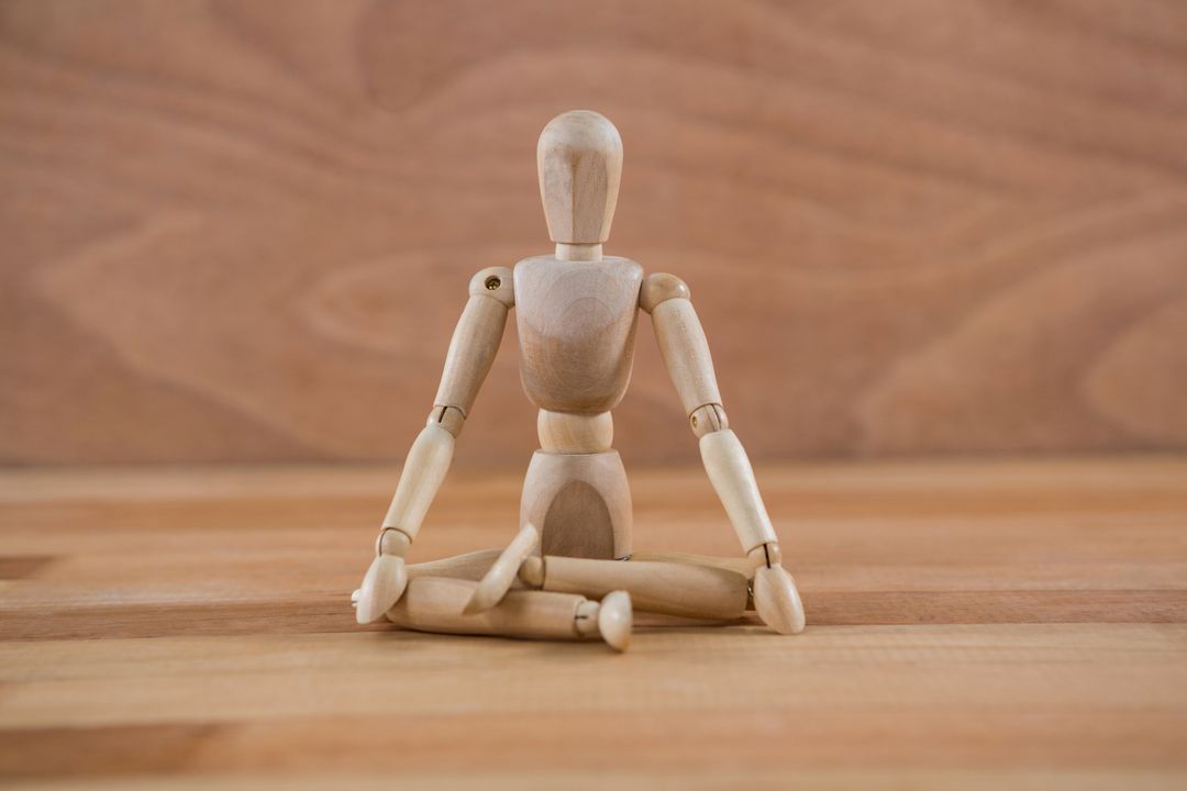 Wooden figurine sitting in a lotus position - Free Images, Stock Photos and Pictures on Pikwizard.com