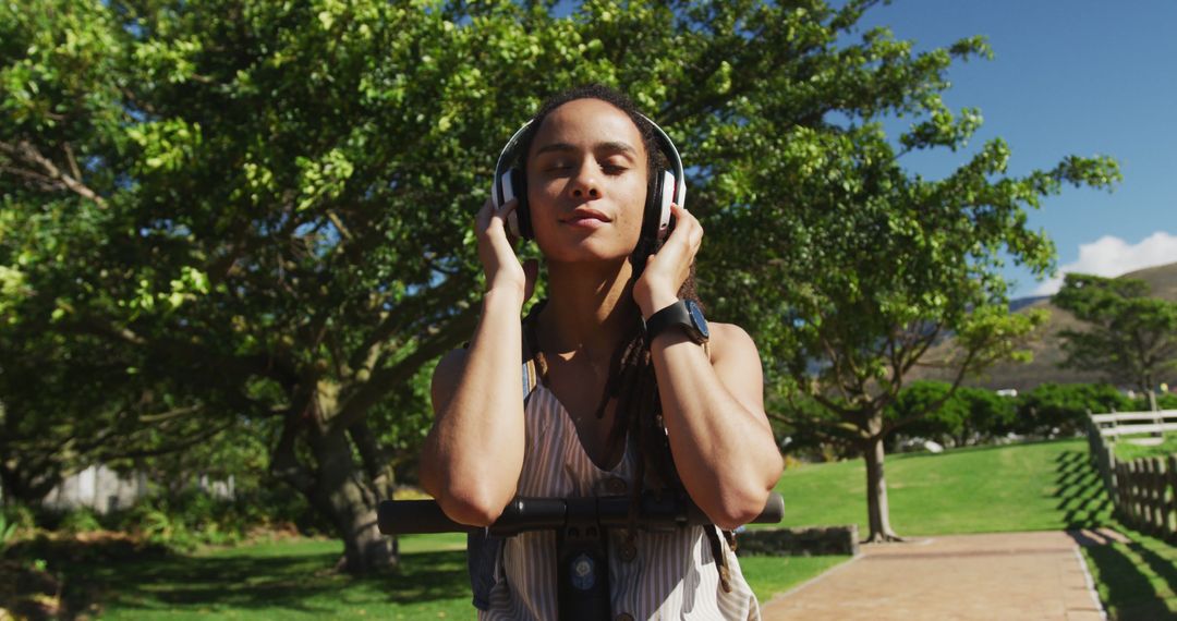 Relaxed Woman Enjoying Music Through Headphones in Sunny Park - Free Images, Stock Photos and Pictures on Pikwizard.com