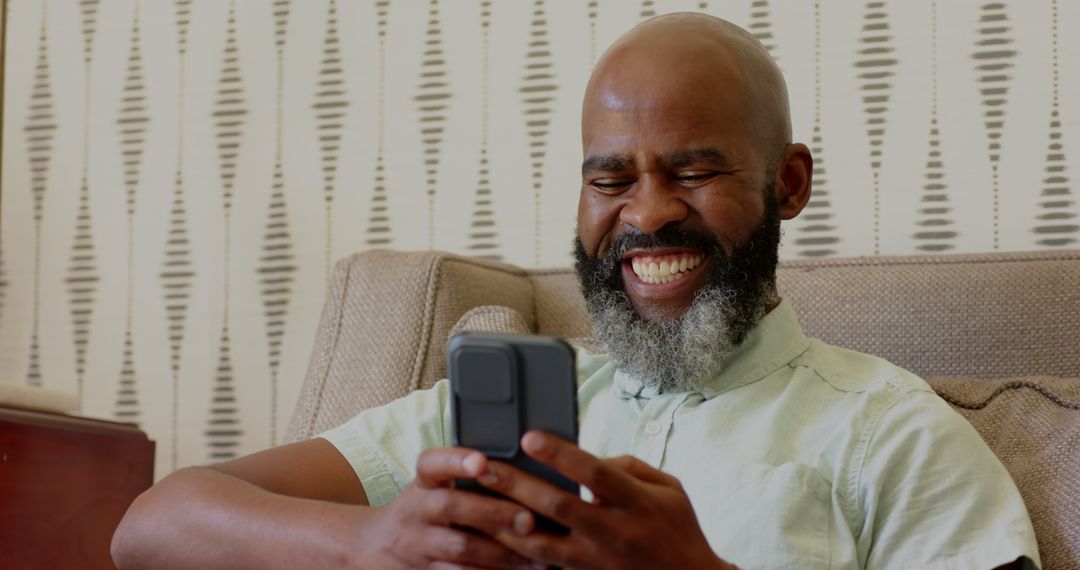 Smiling Man Using Smartphone at Home with Refreshing Drink