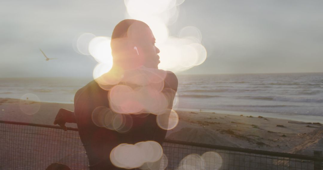 Silhouette of Man with Bokeh Lights Exercising by the Beach