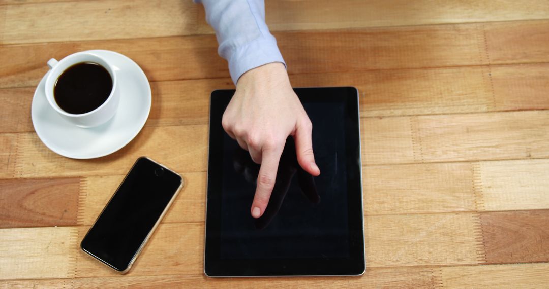 Hand Using Tablet Touch Screen on Wooden Table with Coffee - Free Images, Stock Photos and Pictures on Pikwizard.com