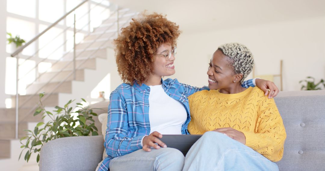 Multicultural Lesbian Couple Using Smartphone on Casual Home Couch