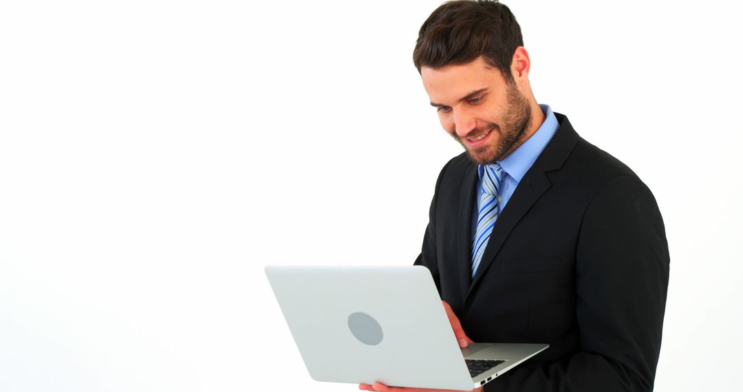 Confident Businessman in Suit Working on Laptop Against White Background - Free Images, Stock Photos and Pictures on Pikwizard.com