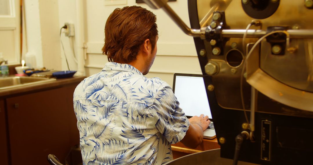 Man Wearing Tropical Shirt Working on Laptop in Workshop - Free Images, Stock Photos and Pictures on Pikwizard.com