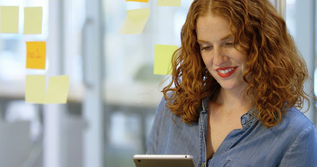 Smiling Redhead Businesswoman Using Tablet in Creative Workspace - Free Images, Stock Photos and Pictures on Pikwizard.com