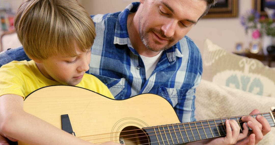 Happy Father and Son Playing Guitar Together on Sofa at Home - Free Images, Stock Photos and Pictures on Pikwizard.com