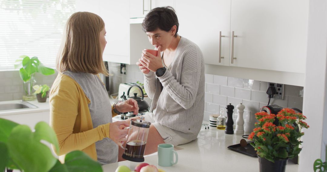 Two friends enjoying coffee together in bright kitchen - Free Images, Stock Photos and Pictures on Pikwizard.com