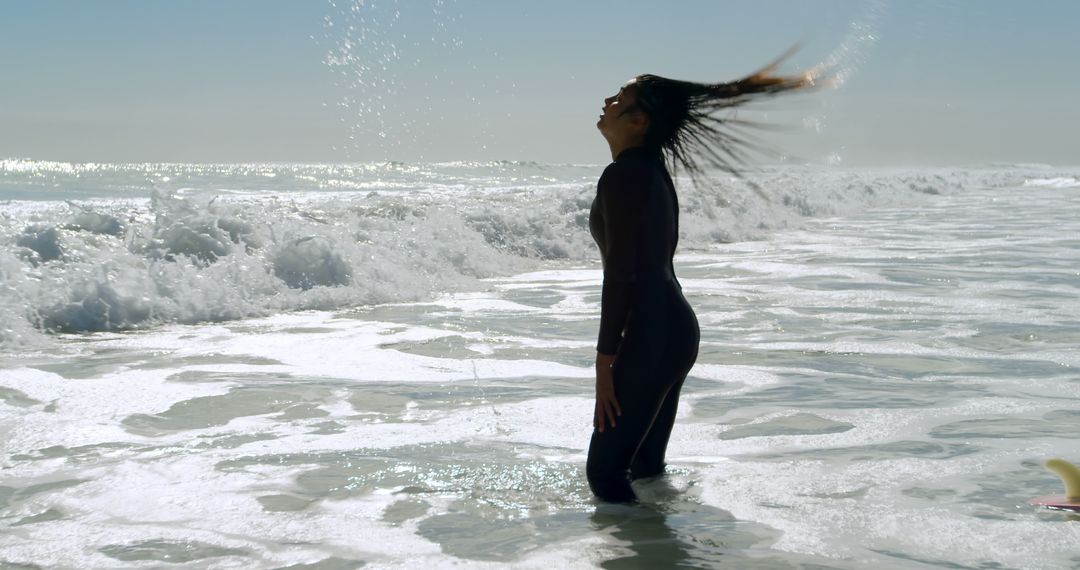 Woman in Wetsuit Enjoying Waves on Sunny Beach - Free Images, Stock Photos and Pictures on Pikwizard.com