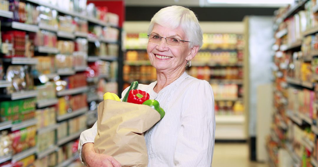 Senior woman grocery shopping in supermarket holding paper bag - Free Images, Stock Photos and Pictures on Pikwizard.com