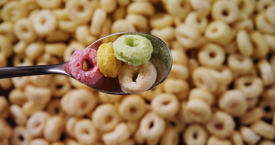 Colorful Cereal Loops on Spoon over Cornflakes Background - Free Images, Stock Photos and Pictures on Pikwizard.com