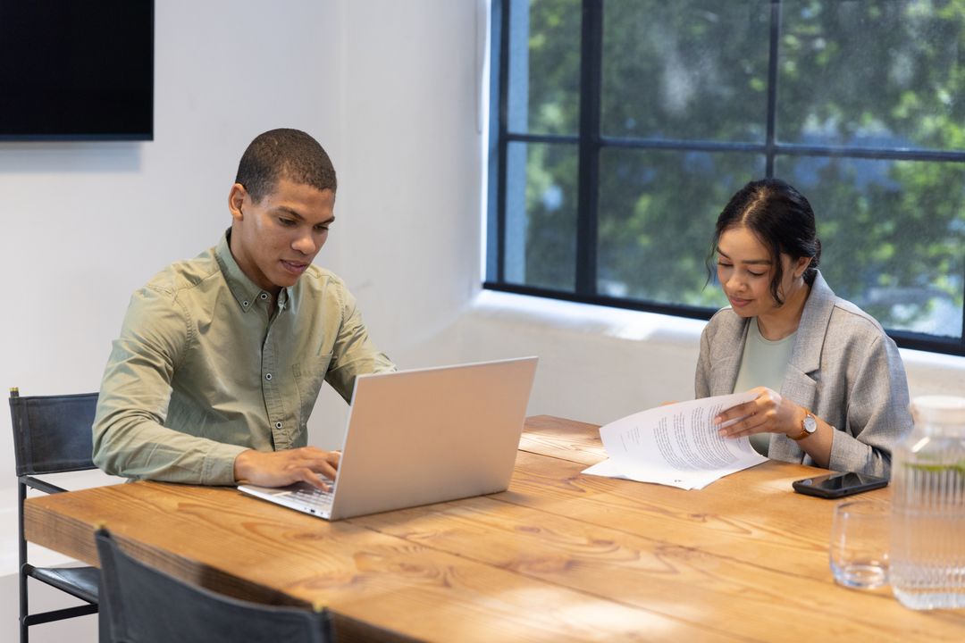 Diverse Team Collaborating with Laptop and Documents in Modern Office
