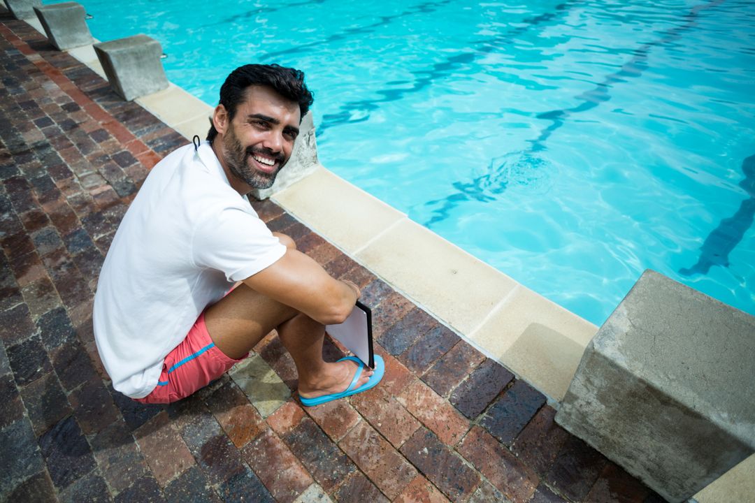 Man Relaxing Poolside Holding Tablet with Smile