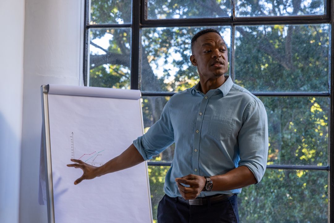 African American Man Presenting Data on Flipchart in Bright Office