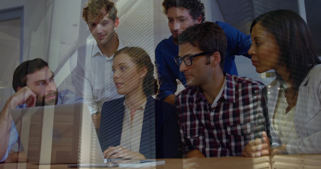 Diverse Group Brainstorming Around Laptop in Office
