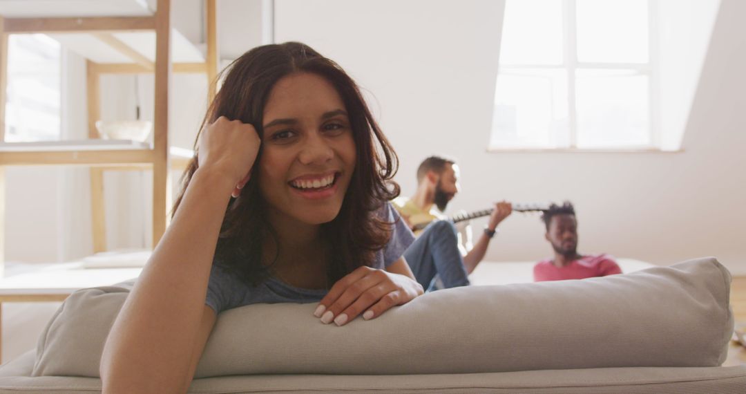 Smiling Woman Relaxing at Home with Friends Playing Guitar