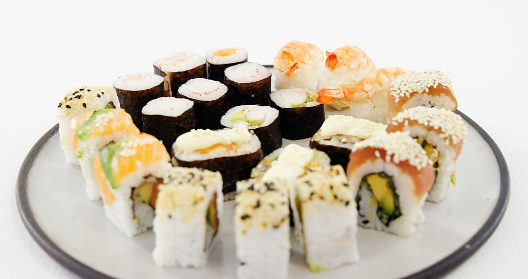 An assortment of sushi rolls is presented on a plate, showcasing a variety of fillings and toppings - Free Images, Stock Photos and Pictures on Pikwizard.com