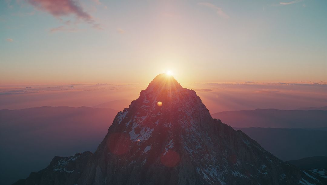 Sunrise Over Jagged Mountain Peak with Lens Flare
