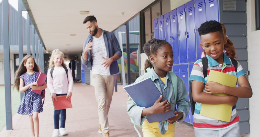 Diverse Teacher Walking with Happy Schoolchildren in School Corridor
