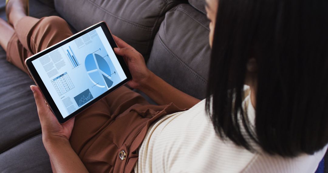 Woman Analyzing Data Charts on Tablet at Home